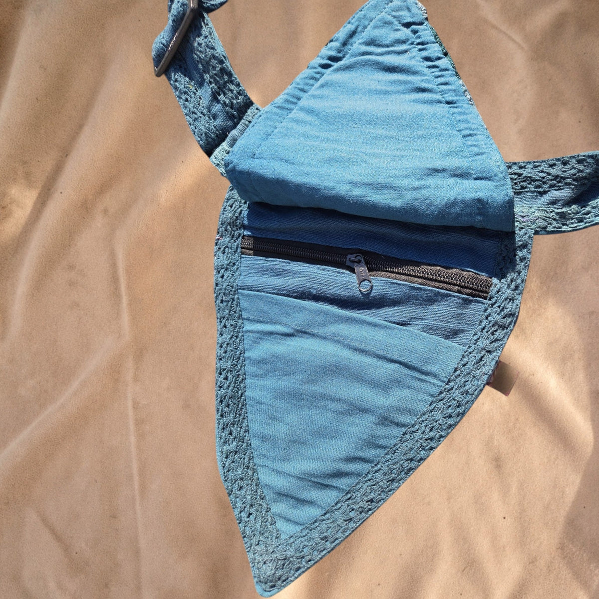 Valentina blue triangular waist bag with decorative leaf stitching, adjustable strap, and multiple zipper pockets.
