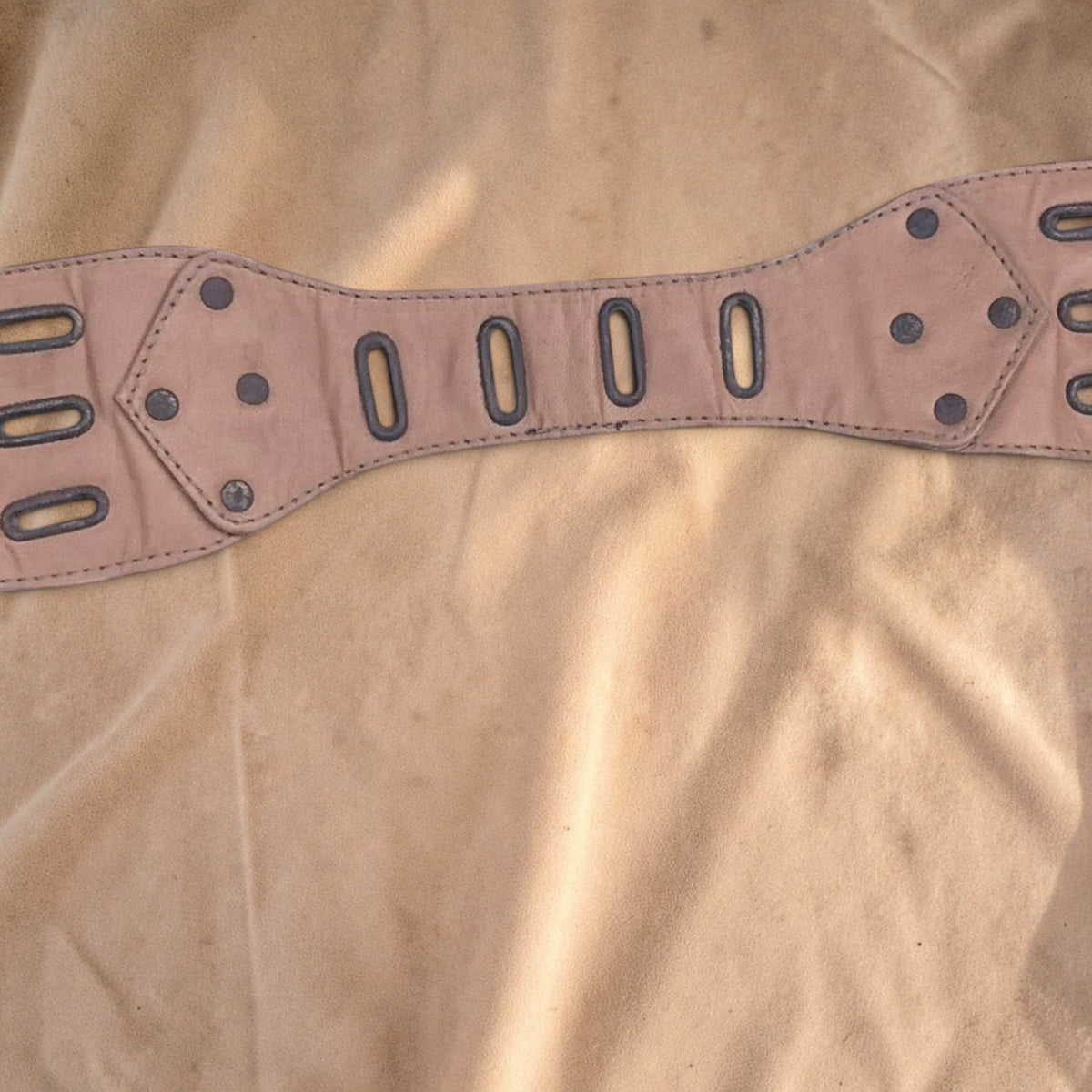 Valentina Savannah waist bag strap in beige leather with metal eyelet details and rivets on a soft fabric background