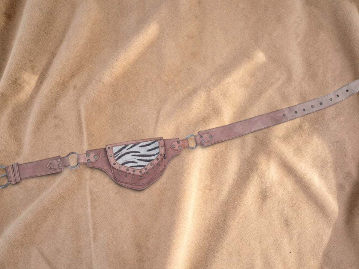 Valentina leather waist bag with zebra print flap, adjustable strap, and metal hardware on a tan fabric background.