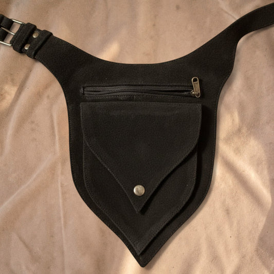 Valentina black leather waist bag with a unique leaf-shaped flap, adjustable strap, and front zipper pocket.
