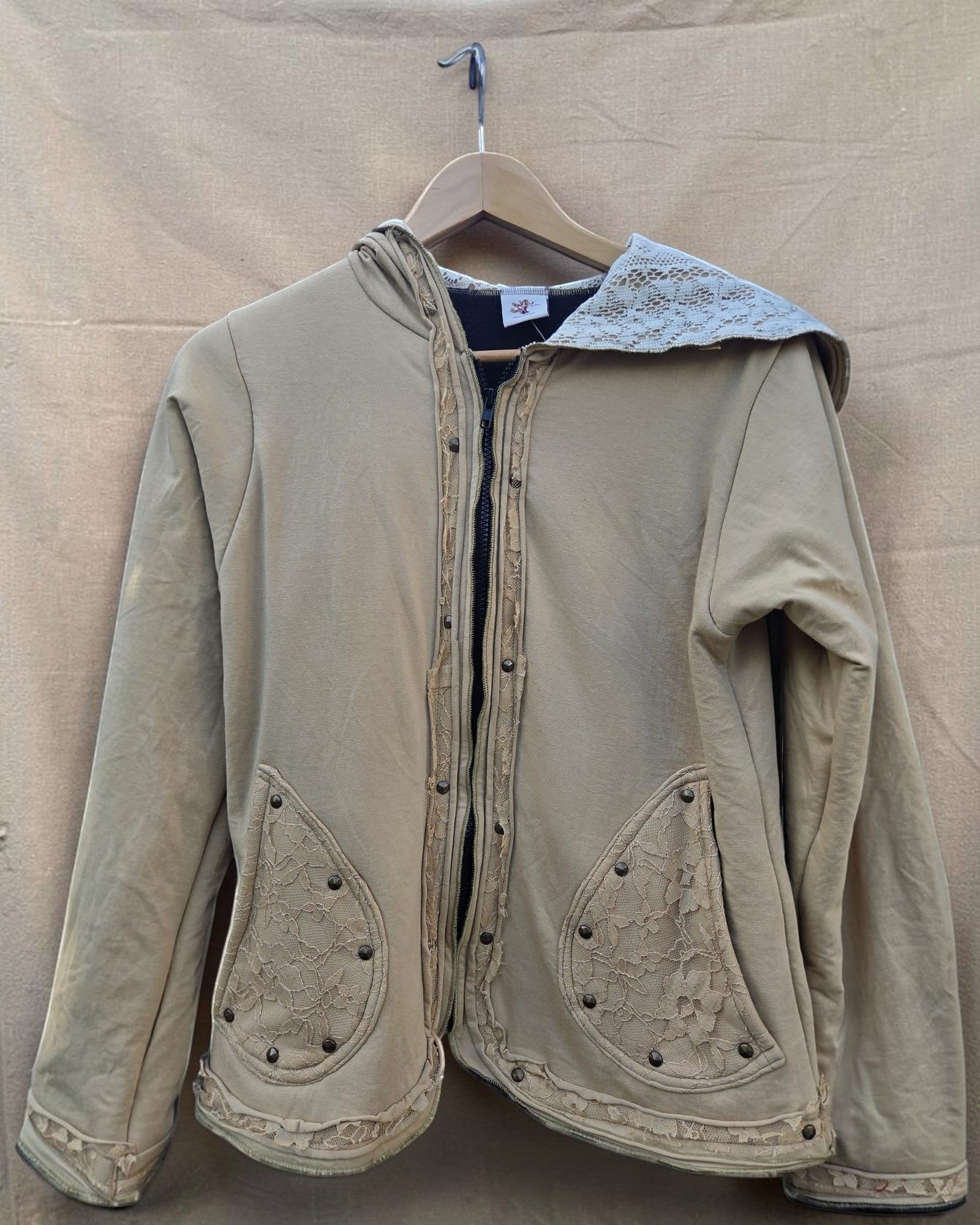Valentina dames hoodie in beige met kanten details en knopen. Capuchon, zakken en zoom zijn versierd met kant.