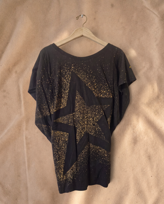 Valentina Dreamcatcher top in zwart met een grote gouden sterrenprint en spikkelpatroon op een houten hanger