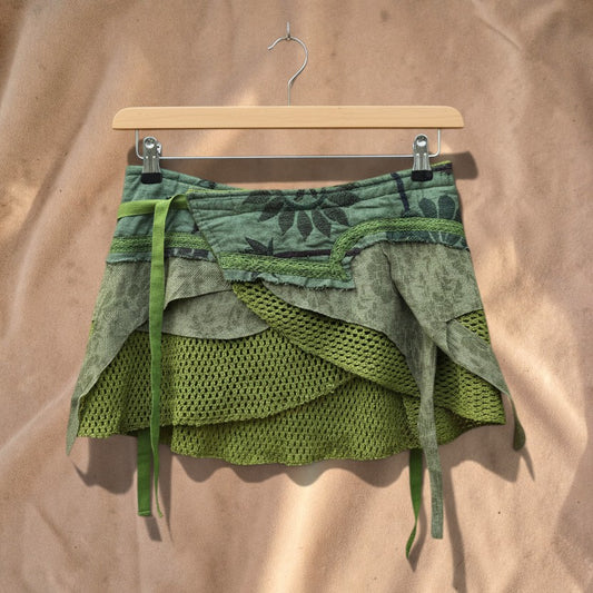 Valentina Moss Veil layered wrap skirt in olive green with open weave textures and organic floral prints on a hanger.