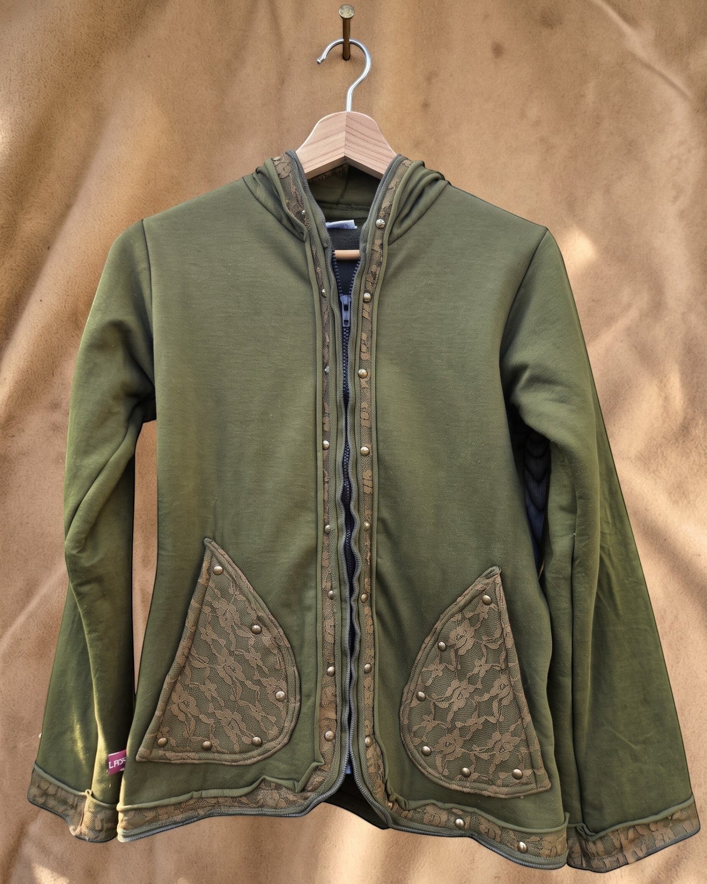 Valentina Soft Nomad jack in olijfgroen met kanten details, capuchon en drukknopen op een houten kledinghanger.