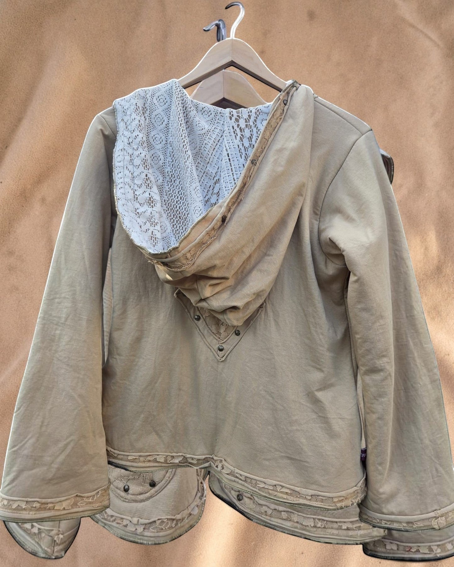 Valentina Soft Nomad Jacket in beige katoenmix met kanten details op de capuchon en zoom, hangend aan een kledinghanger.