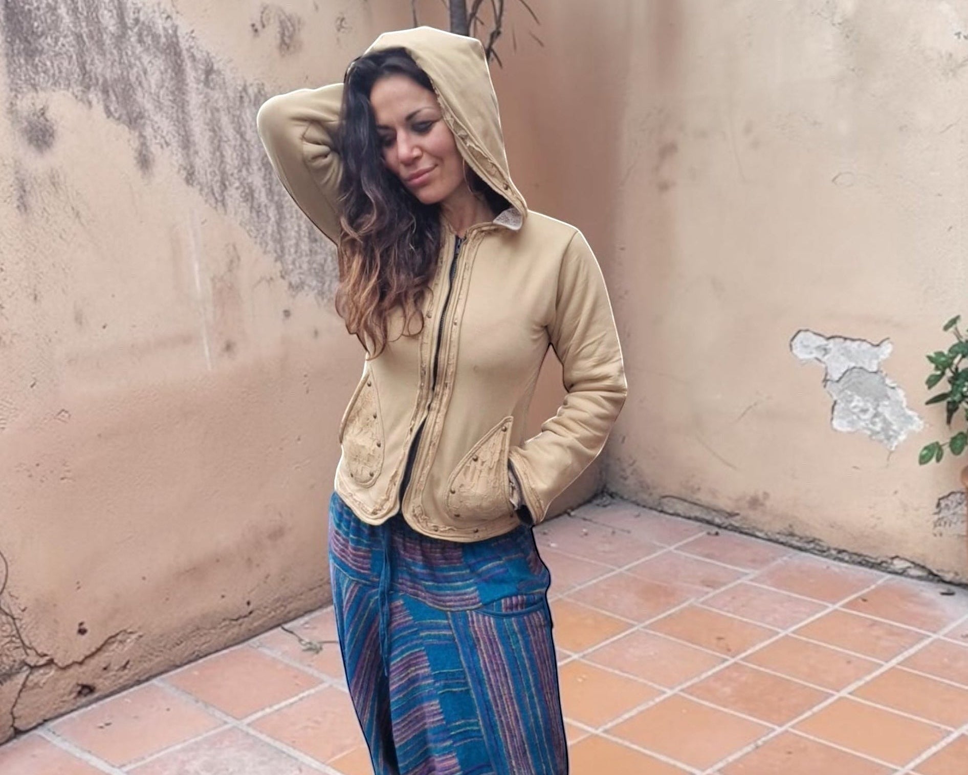Valentina Soft Nomad Jacket in beige katoen met kanten details en capuchon, gedragen door een vrouw op een terras.