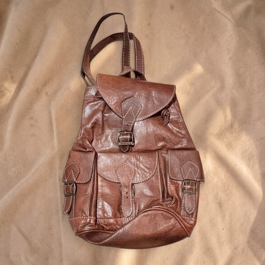 Valentina Trail brown leather backpack with multiple front pockets, adjustable straps, and a classic artisan design.