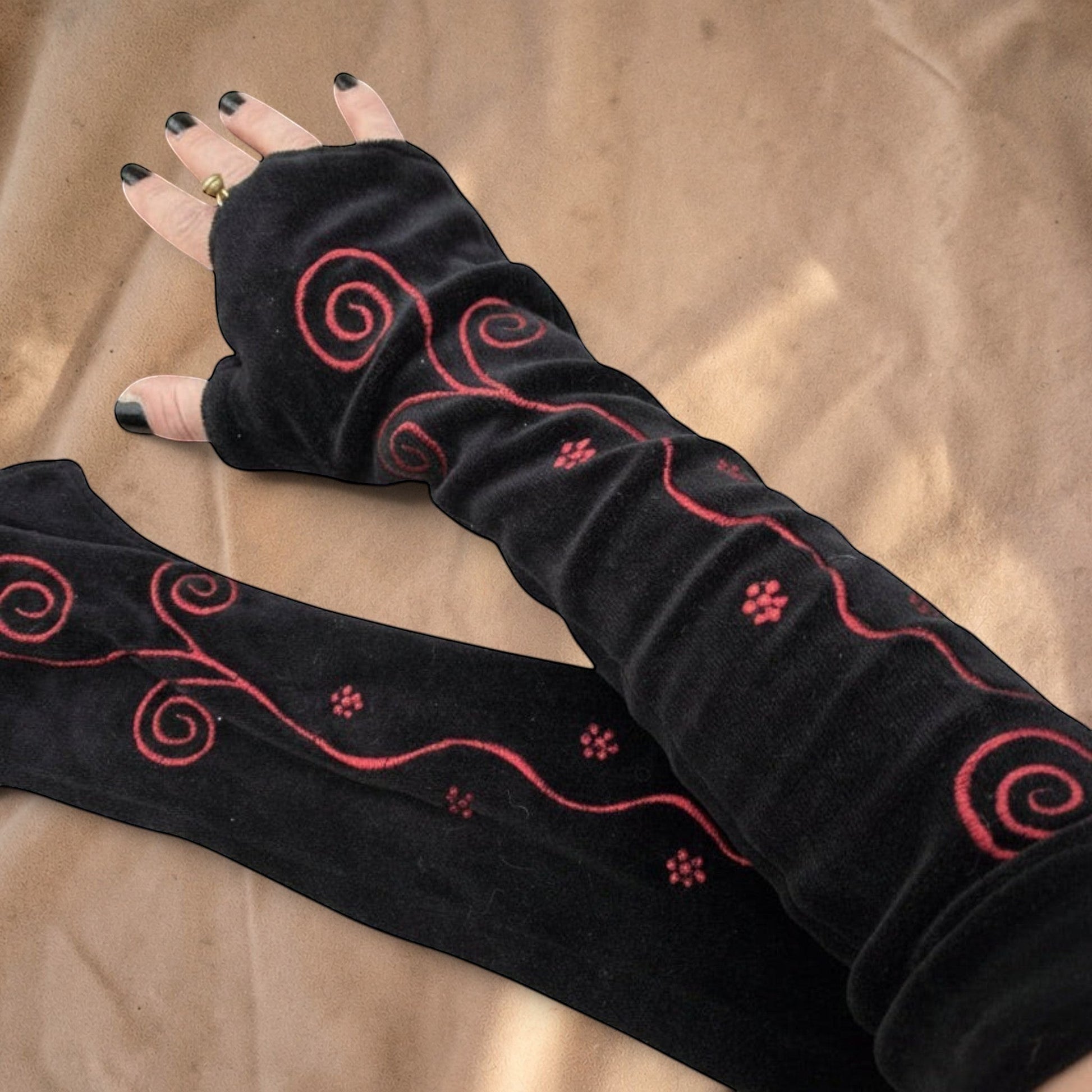 Valentina zwarte velvet armwarmers met rode geborduurde spiraalpatronen en bloemdetails voor een festivalstijl.