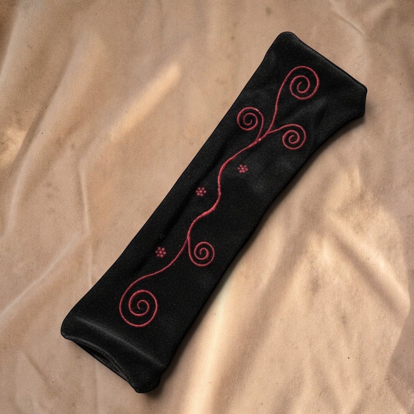 Valentina Ritual Spiral armwarmers van zwart velvet met rood geborduurde spiraalpatronen en lichte stretch.
