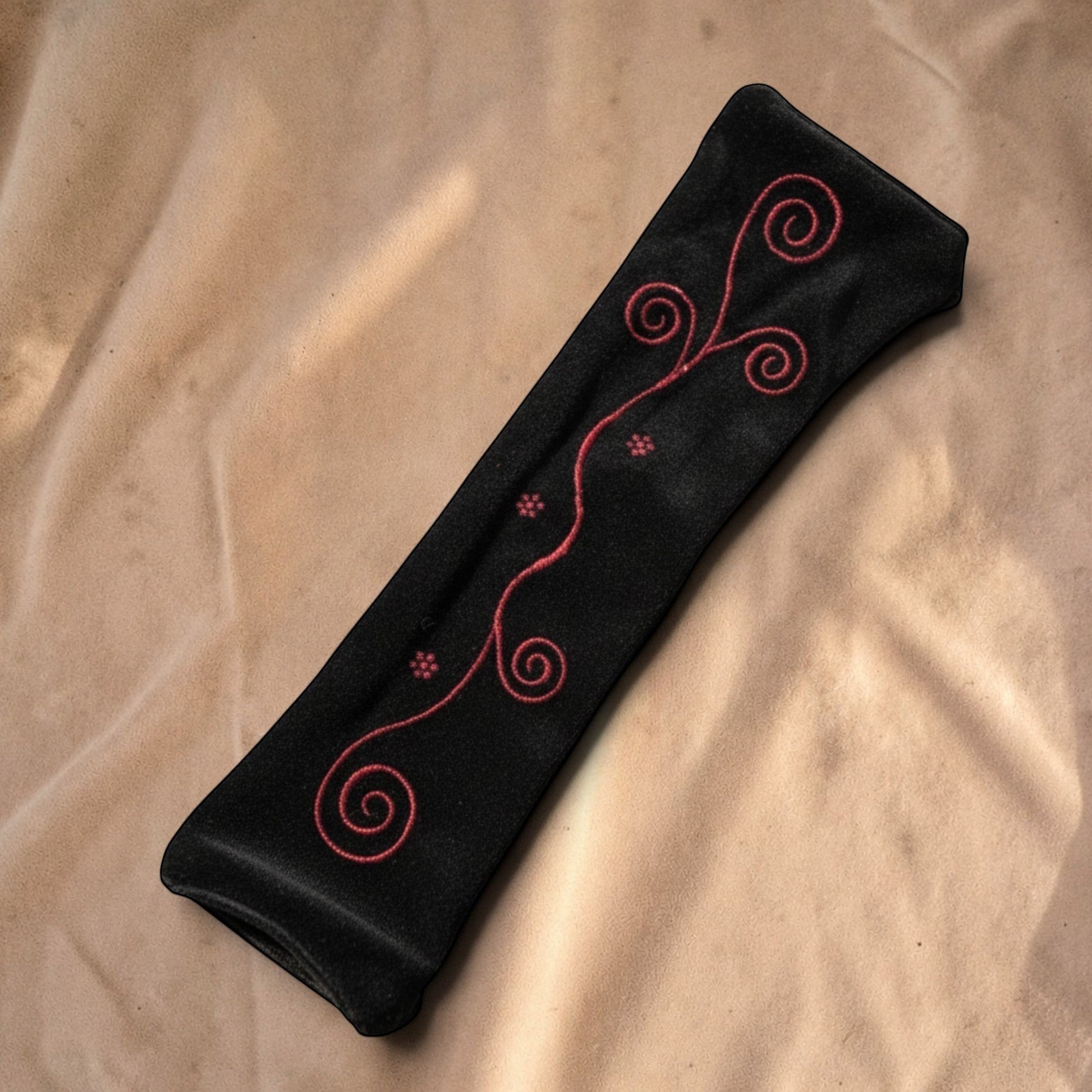 Valentina Ritual Spiral armwarmers van zwart velvet met rood geborduurde spiraalpatronen en lichte stretch.